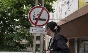 A woman walks past a no smoking sign outside a shopping centre in Bangkok, Thailand.