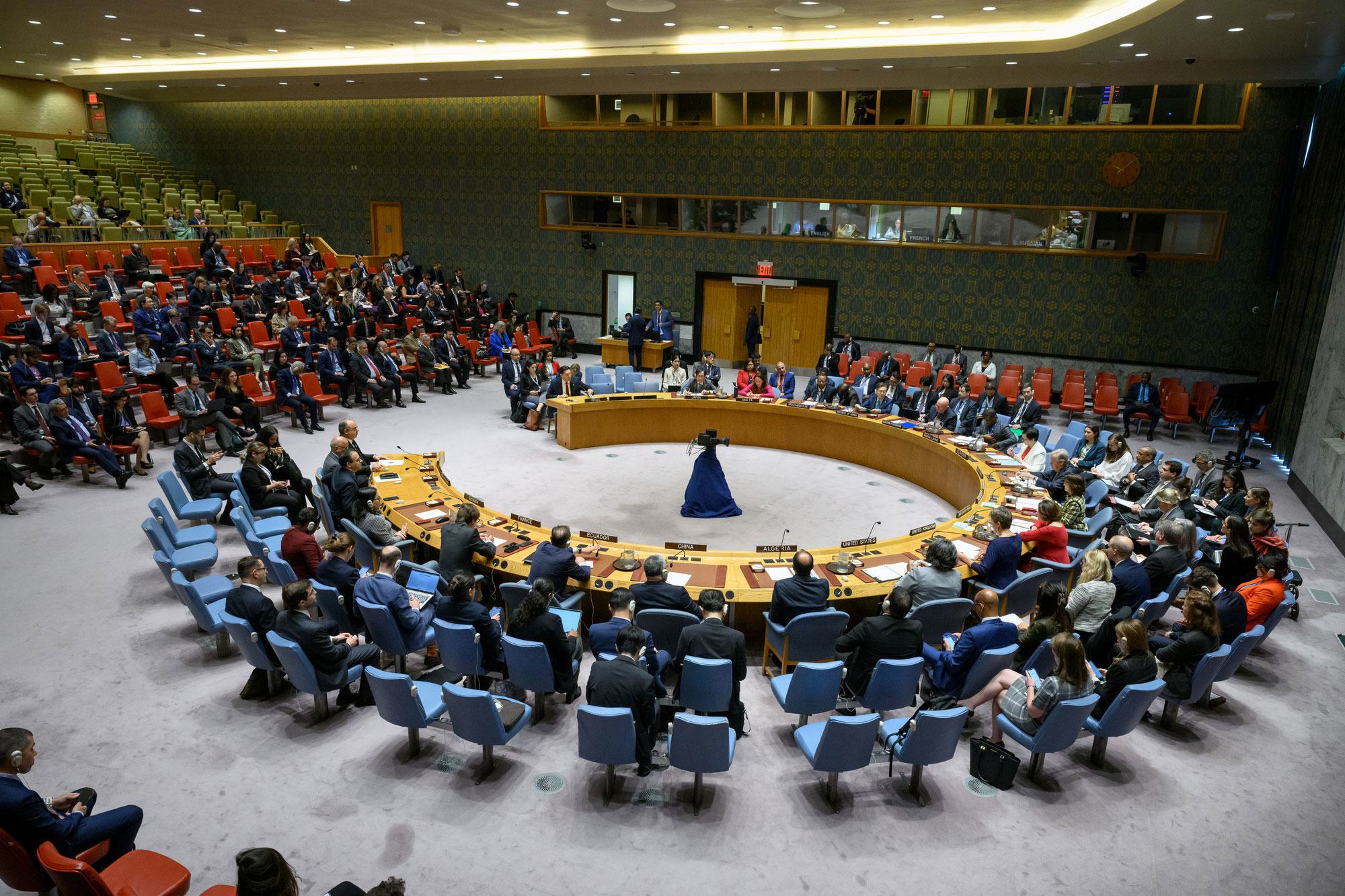 Picha pana ya mkutano rasmi katika chumba cha Baraza la Usalama UMOJA WA MATAIFA huko New York, huku wajumbe wakiwa wameketi kuzunguka meza ya duara na hadhira kwenye ghala.