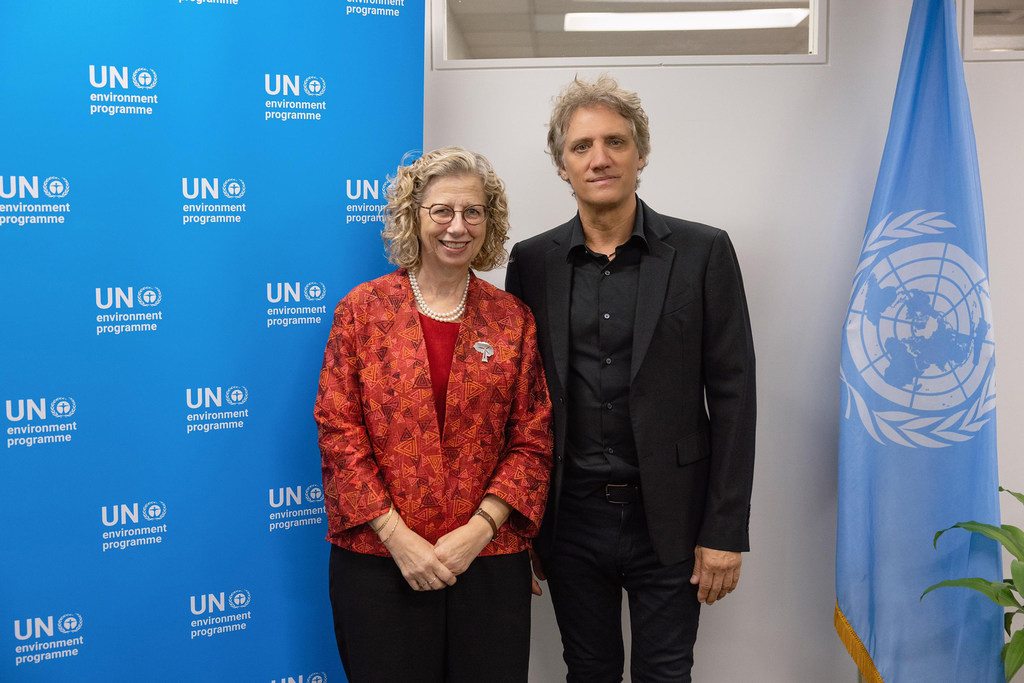 El músico argentino Charly Alberti y la directora ejecutiva del PNUD, Inger Andersen, posan para una foto frente a un telón de fondo azul del PNUD .