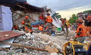 Rescue workers in the Philippines search a building in Bogo City, following the earthquake in Cebu.