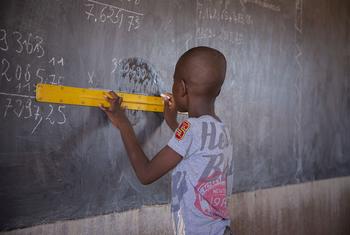 Um aluno usa uma régua no quadro negro em sala de aula, numa escola pública em Kaya, região Centro-Norte, Burkina Faso