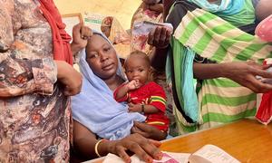 A mother receives her monthly cash payment as part of the Mother and Child Cash Transfer Plus (MCCT+) programme in Sudan.