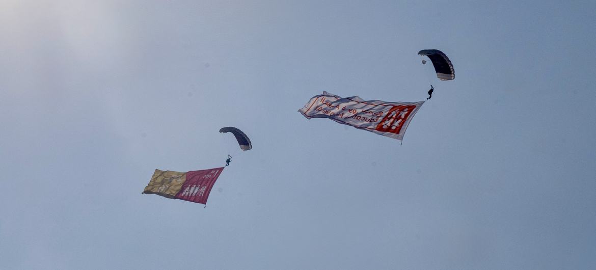A team of parachutists descend over the QNCC, each carrying a flag representing one of the 17 Sustainable Development Goals. A team of parachutists descend over the QNCC, each carrying a flag representing one of the 17 Sustainable Development Goals.