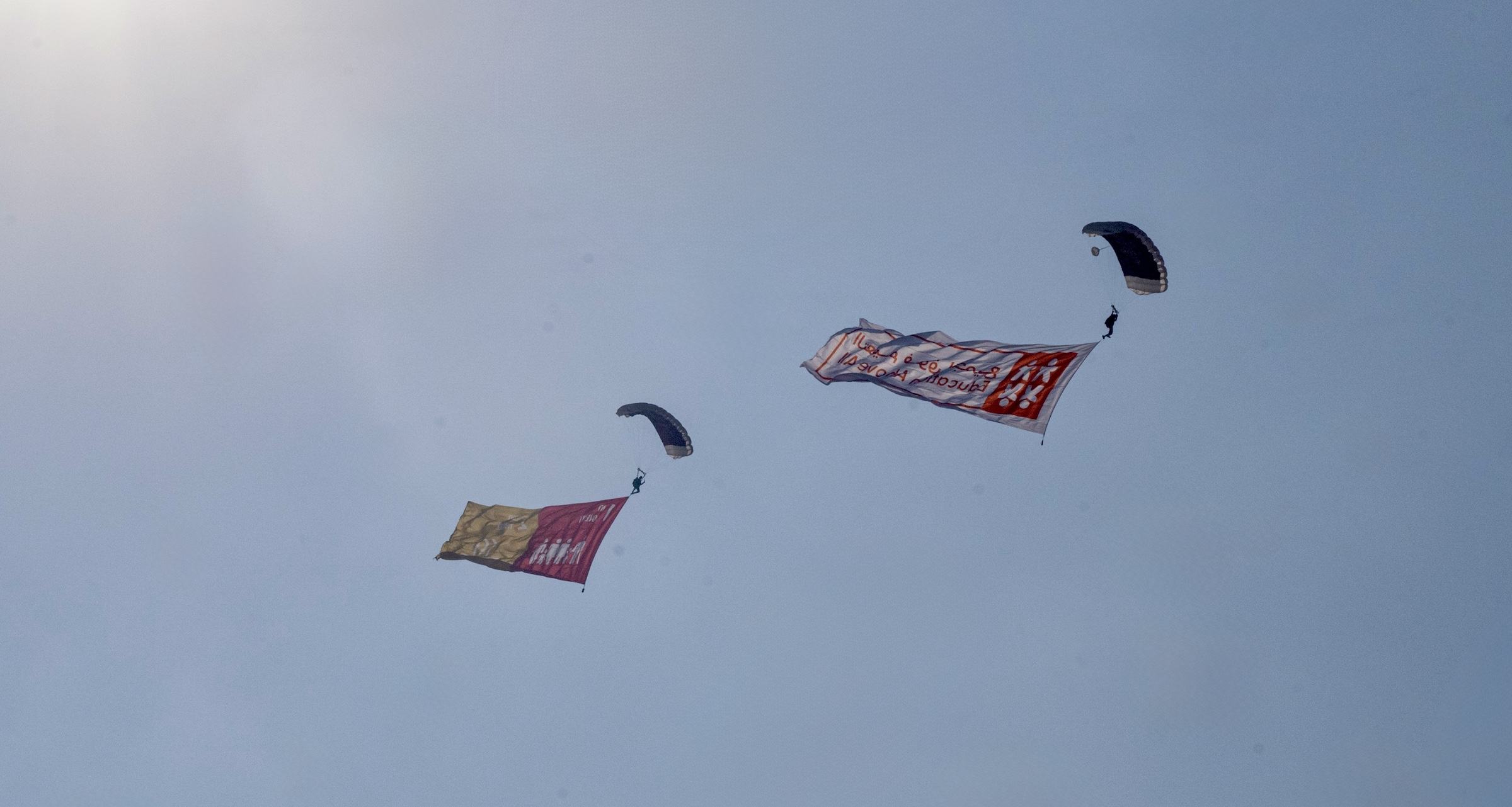 Une équipe de parachutistes descend au-dessus du QNCC, chacun portant un drapeau représentant l'un des 17 objectifs de développement durable.