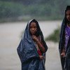 Duas meninas envoltas em lonas plásticas ficam na chuva durante uma enchente no Nepal.
