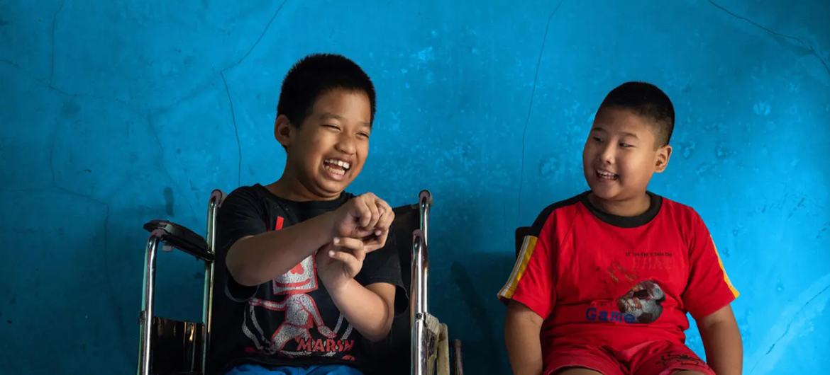 Un niño de 12 años con discapacidad física se sienta junto a su mejor amigo, un niño de 9 años con discapacidad visual, en Java Central, Indonesia.