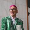 O ativista Ivan Baron, de cabelo rosa e óculos, sorri enquanto veste uma jaqueta verde estampada.