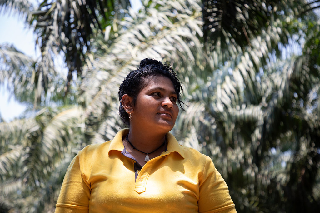 María Alemán, portavoz de la Cooperativa Brisas del Aguán, al aire libre frente a palmeras en Tocoa, Honduras.