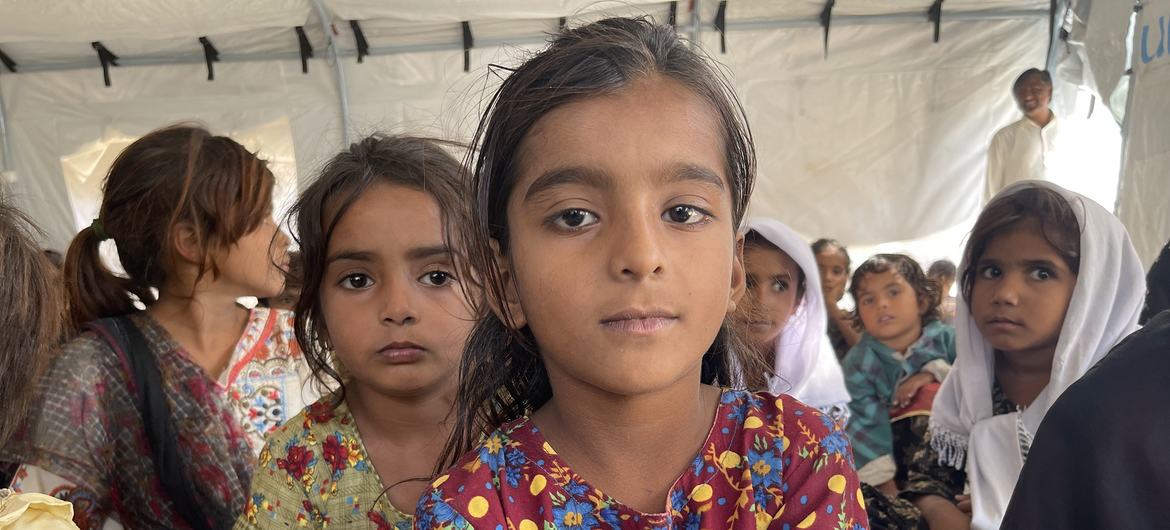 پاکستان میں 2022 کے سیلاب کی وجہ سے بے گھر ہونے والے خاندانوں کے بچے ایک عارضی امدادی پناہ گاہ میں بیٹھے ہیں۔
