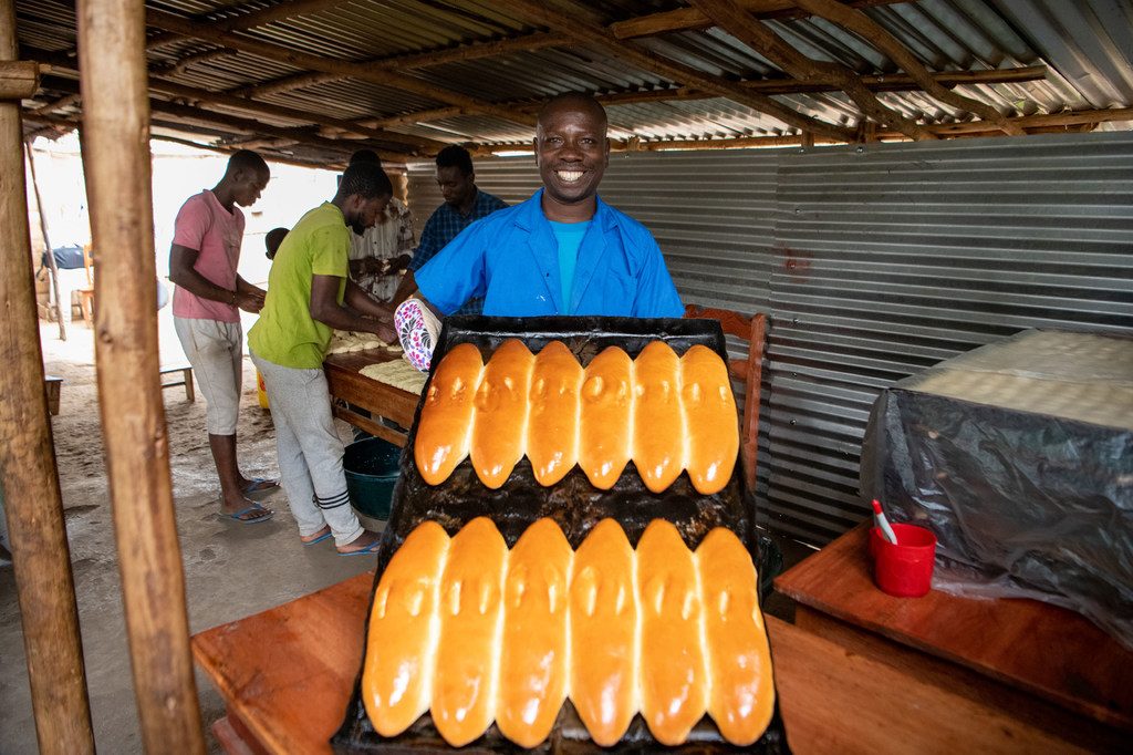 Cadet Kavugwa Shebulike pose avec son pain fraîchement cuit dans sa boulangerie du camp de réfugiés de Nyankanda.