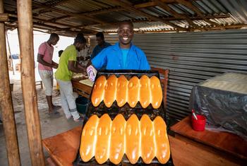 Kavugwa Shebulike Cadet, a baker and a refugee from the Democratic Republic of the Congo poses with his freshly baked bread at his bakery in Nyankanda refugee camp.