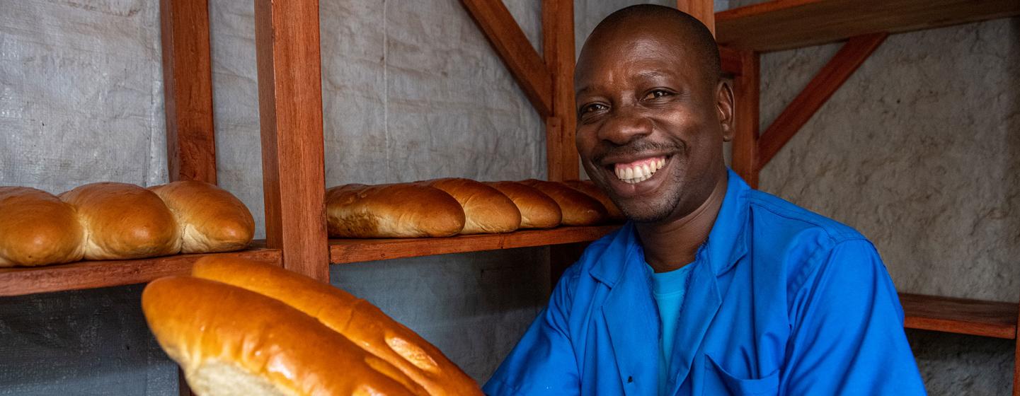Cadet Kavugwa Shebulike, un boulanger et un réfugié de la République démocratique du Congo pose avec son pain fraîchement cuit dans sa boulangerie du camp de réfugiés de Nyankanda.