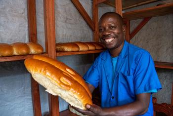 Cadet Kavugwa Shebulike, un boulanger et un réfugié de la République démocratique du Congo pose avec son pain fraîchement cuit dans sa boulangerie du camp de réfugiés de Nyankanda.