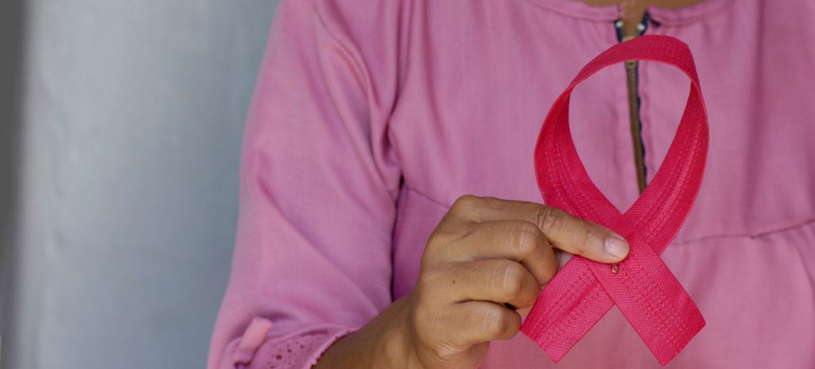 Une femme tient un ruban rose en signe de sensibilisation à la Journée du cancer du sein.