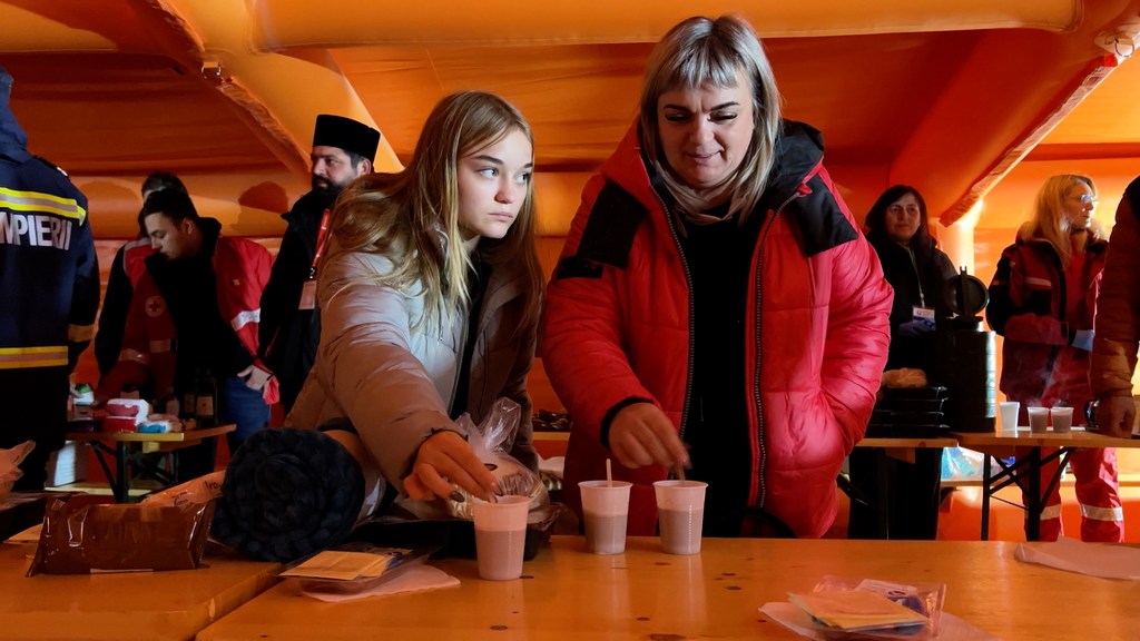 Larysa Kirilenko from Donetsk and her daughter take a snack on at a waystation en route to Bucharest.