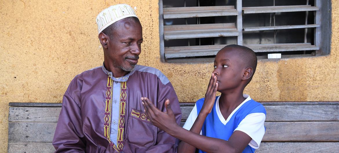 A boy who is hard of hearing teaches his father sign language in Bouaké, Côte d'Ivoire.