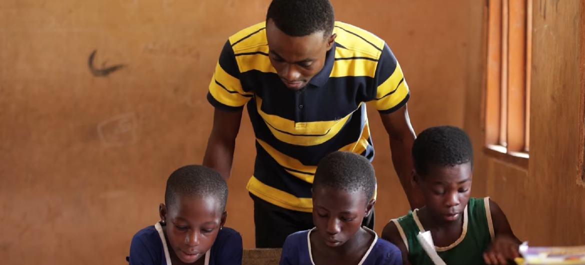 A teacher at a school in Ghana works alongside his pupils. 