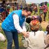 Mfanyakazi wa misaada UNHCR aliyevaa fulana ya bluu akizungumza na familia ya wakimbizi katika eneo la kuhamishiwa nchini Burundi.