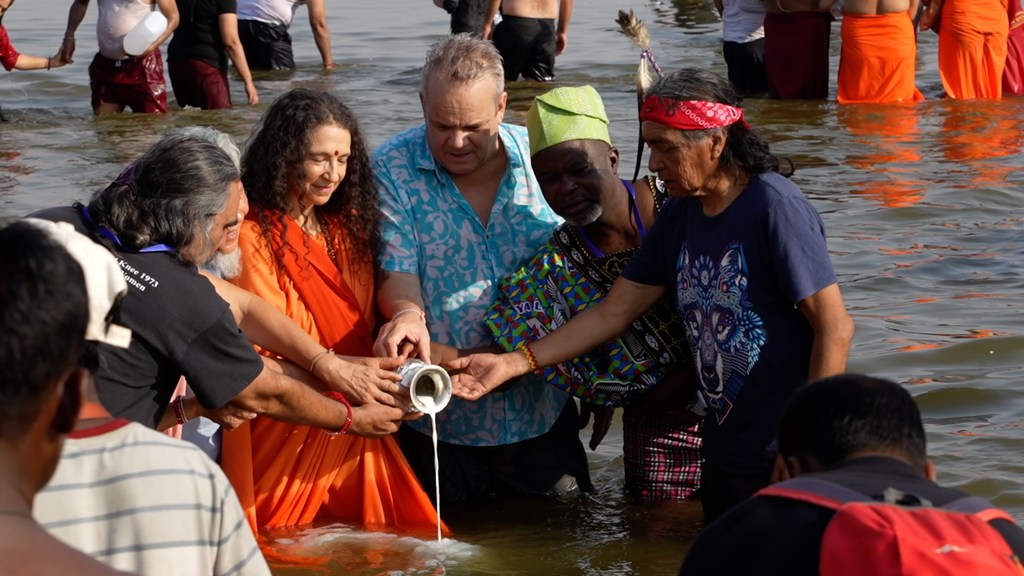 UNESCO के निदेशक टिम कर्टिस भारत के प्रयागराज में महाकुंभ उत्सव के दौरान एक पात्र से नदी में तरल पदार्थ डालने की रस्म में भाग लेते हैं।