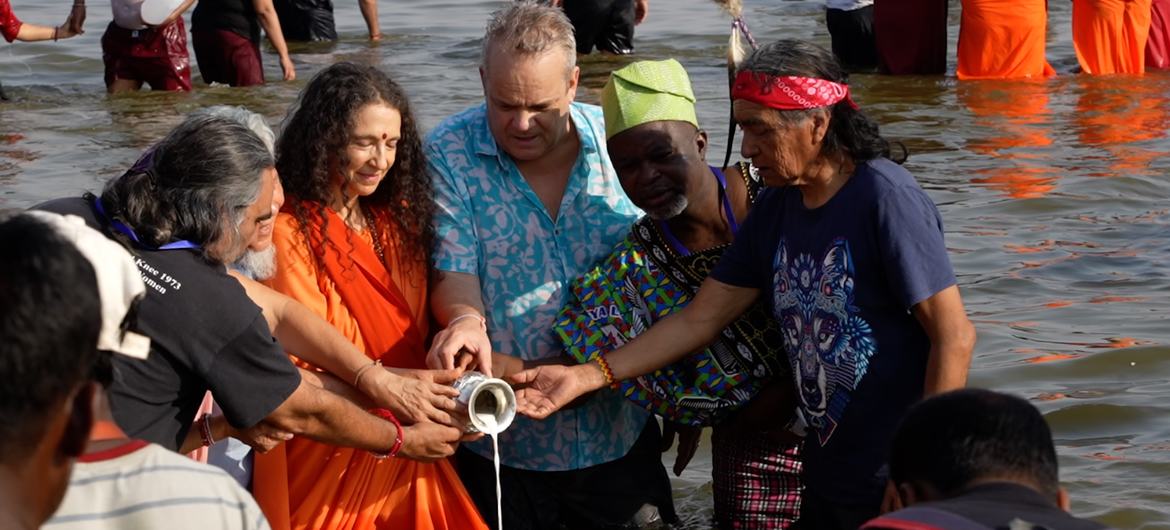 UNESCO के निदेशक टिम कर्टिस भारत के प्रयागराज में महाकुंभ उत्सव के दौरान एक पात्र से नदी में तरल पदार्थ डालने की रस्म में भाग लेते हैं।