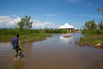 A man walks in floodwaters in Gatumba, Burundi an area which is receiving unpredictable rainfall due to climate change.