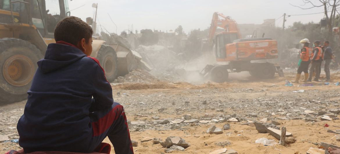 在加沙地带南部拉法市以东的纳赛尔居民区，一名儿童看着尸体从房屋废墟下挖出。 