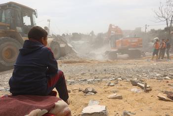 A child watches as bodies are recovered from under the rubble of a house in the Al-Nasr neighborhood, east of the city of Rafah, in the southern Gaza Strip.