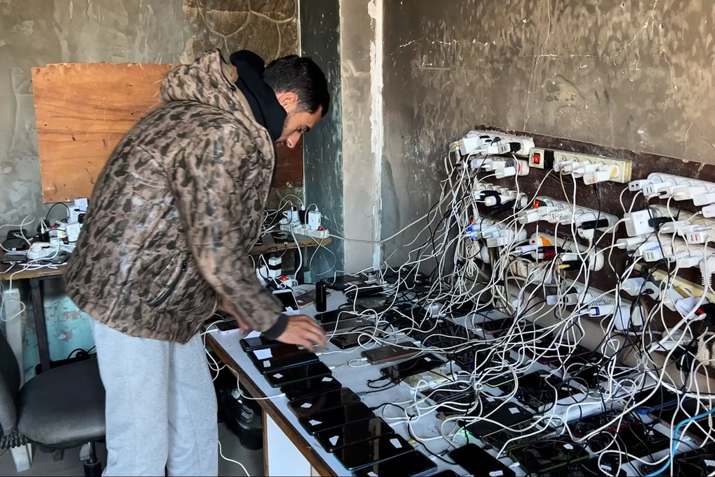 En la ciudad de Gaza, Salah Hammami organiza una gran cantidad de teléfonos y baterías sobre una mesa para cargarlos.