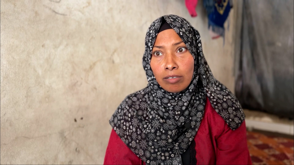 Ibtihal Abu Dabbagh, una mujer palestina, carga su teléfono mientras vive en una tienda de campaña junto a su casa destruida en Gaza.