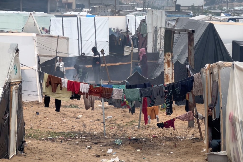 Un campamento de refugiados improvisado en la ciudad de Gaza durante el invierno, con ropa secándose en un tendedero y gente entre las tiendas de campaña.