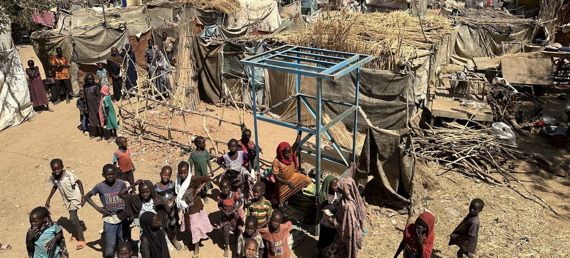 Children and their families stand near temporary shelters at an IDP camp in Zelingei town, central Darfur, Sudan.