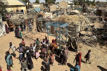 Children and their families stand near temporary shelters at an IDP camp in Zelingei town, central Darfur, Sudan.