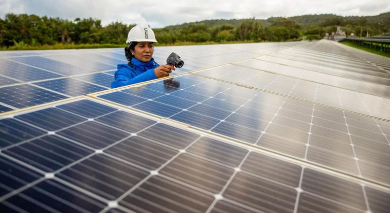 Seorang wanita bekerja di pertanian energi surya di Mauritius.