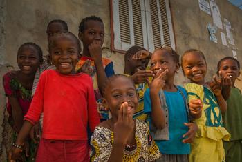 A group of smiling Senegalese children posing for a photo in front of a building.