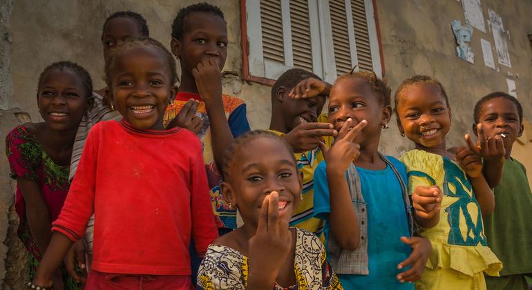 Un grupo de niños senegaleses sonrientes posan para una foto frente a un edificio.