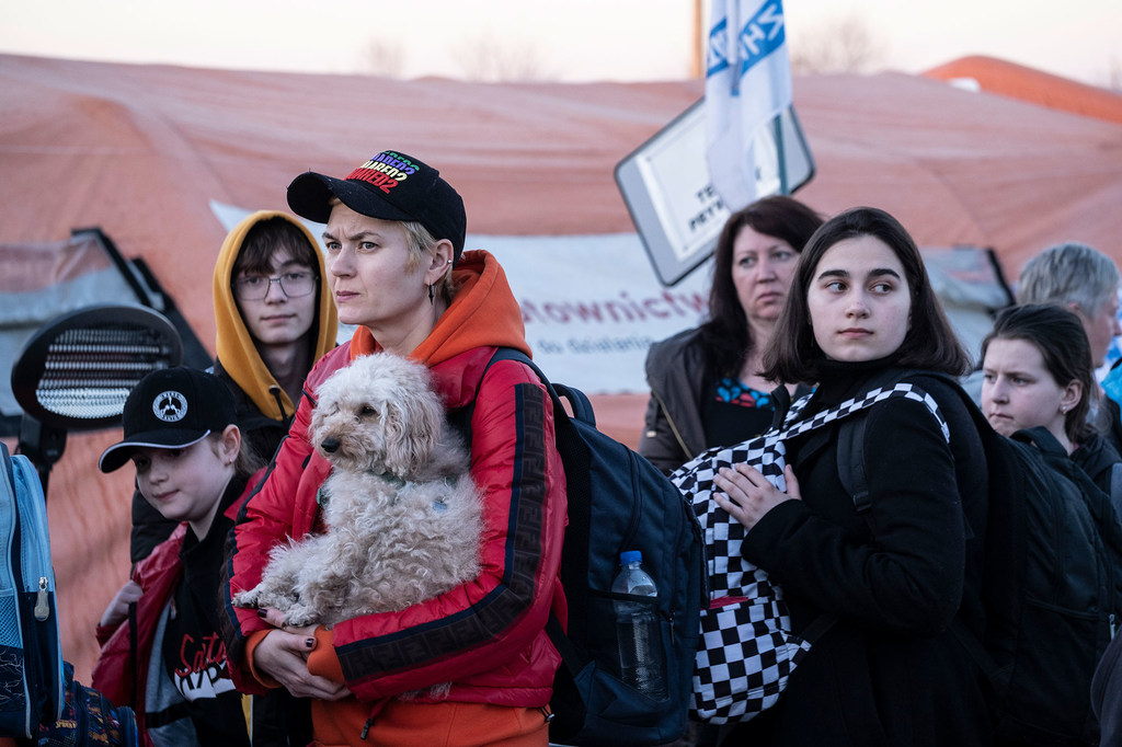Беженцы, в том числе женщина с собакой на руках, стоят в очереди на пограничном переходе из Украины в Польшу.