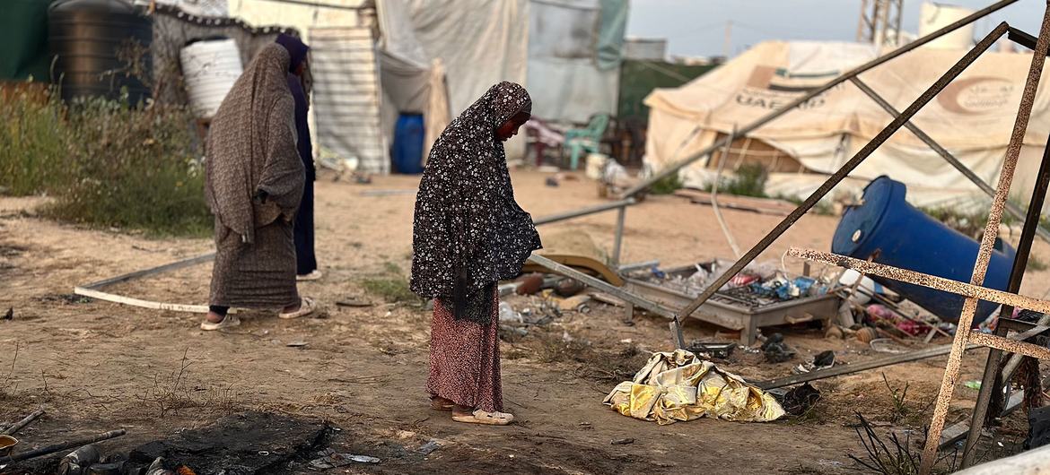 Women stand in a damaged displacement settlement in Khan Younis, Gaza.