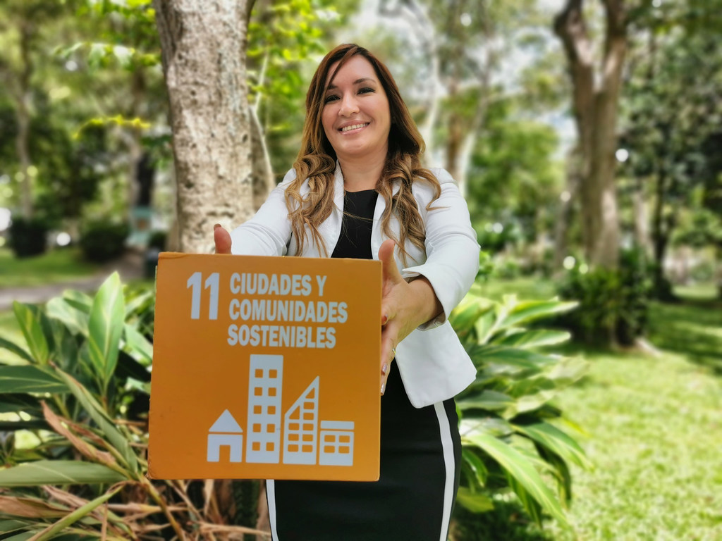 Iris Arroyo sostiene un cartel del ODS 11, Ciudades y Comunidades, en un parque de Costa Rica.