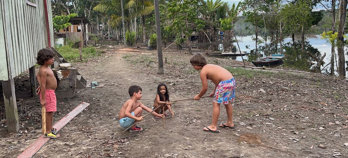 Crianças brincam às margens do Rio Negro, um afluente do Rio Amazonas, no noroeste do Brasil