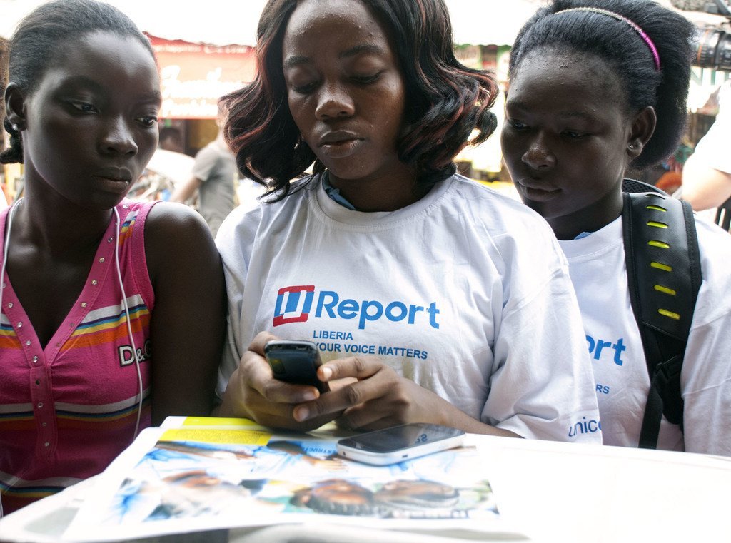 Jóvenes leyendo información en un teléfono celular en Monrovia, Liberia.