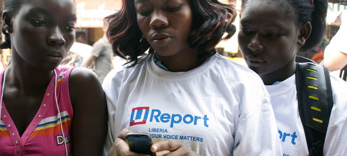 Des adolescentes au Libéria lisent des informations sur un téléphone portable dans le quartier West Point de Monrovia, la capitale.