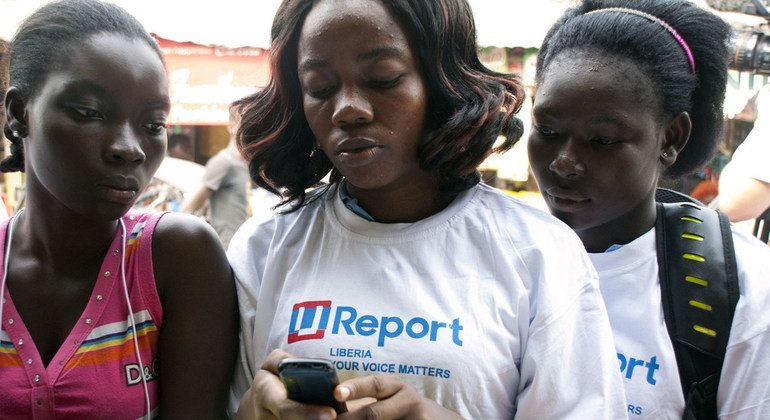 Jóvenes leyendo información en un teléfono celular en Monrovia, Liberia.