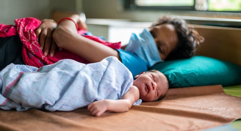 भारत के गुजरात राज्य के एक अस्पताल में अपने नवजात शिशु के साथ एक महिला.   