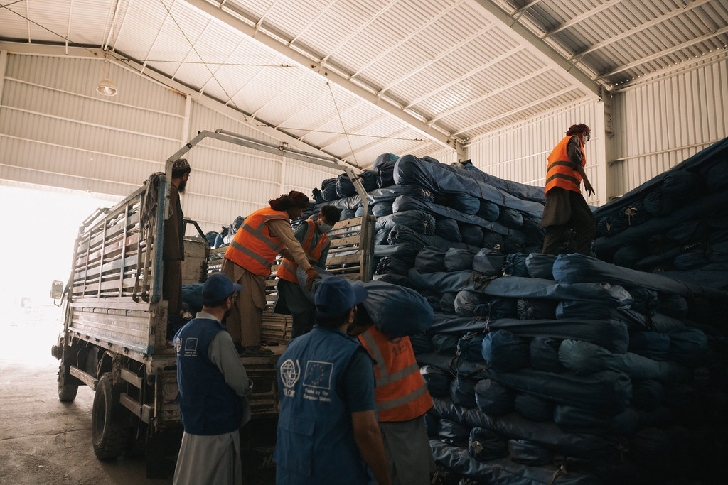 Trabalhadores humanitários da OIM carregam itens de ajuda emergencial em um caminhão dentro de um armazém em Cabul, Afeganistão.