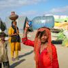 A nine-year-old girl carries water, which she filled from a handpump in a flooded village in Sindh Province, Pakistan.