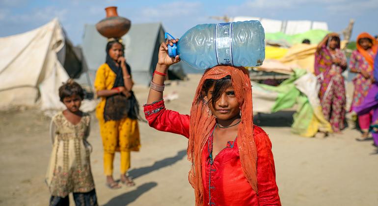 在巴基斯坦信德省一个被洪水淹没的村庄里，一名9岁的女孩通过手泵灌满了一桶水。