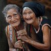 Two elderly Vietnamese women in traditional attire share a joyful moment, symbolizing community resilience and hope during the UN75 anniversary celebrations.