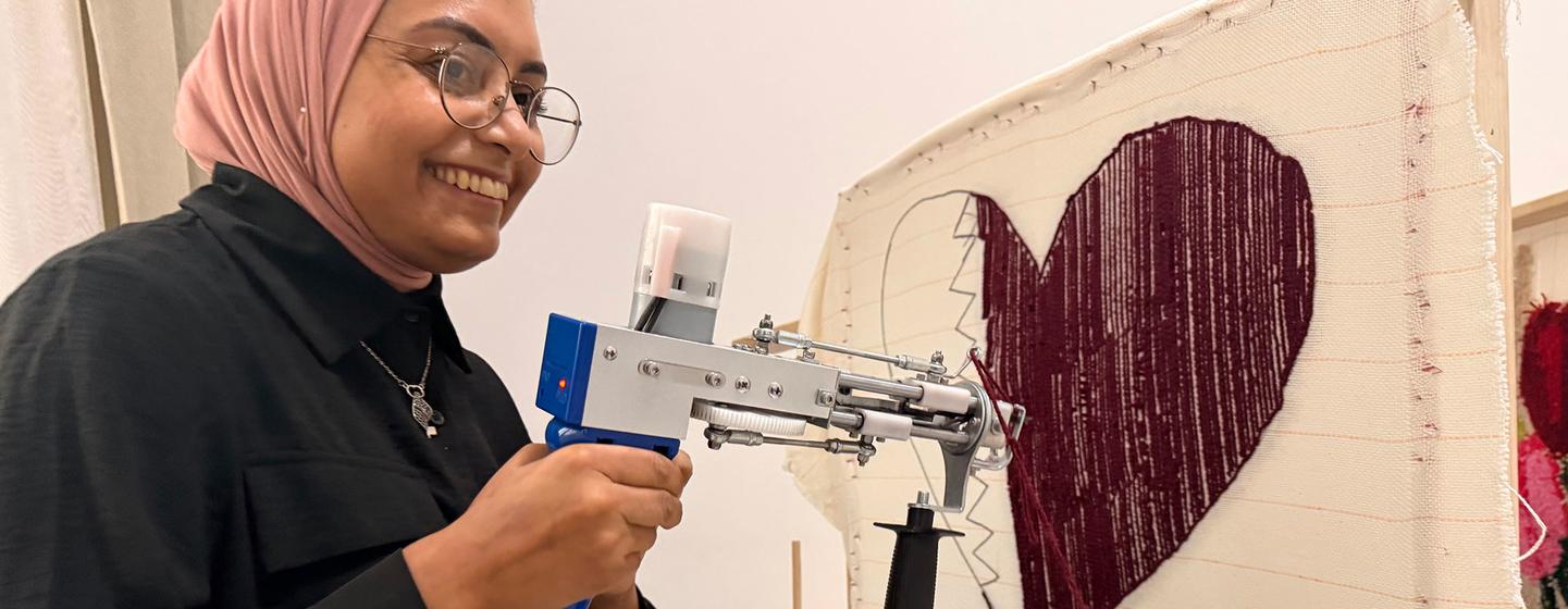 A woman uses a tufting machine to make a rug at the the Al-Thumama complex.