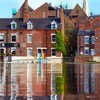 Una calle inundada con reflejos de edificios de ladrillo, incluido el pub Lowther, en York, Reino Unido.