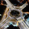 Vista aérea de uma rotunda na Costa Rica à noite, com o trânsito fluindo pela intersecção.